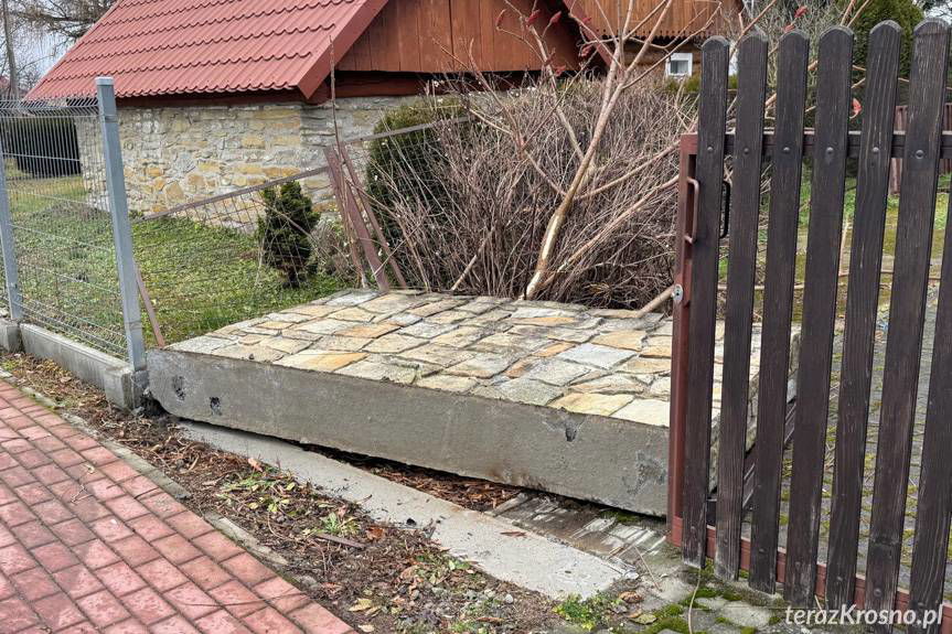 Przewrócone ogrodzenie i uszkodzony opel